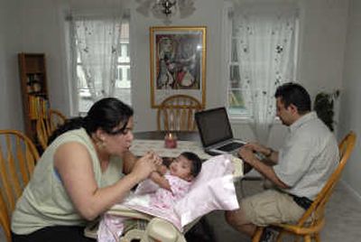 Patricia Ortiz plays with her 12-week-old daughter, Valentina, as her husband, Sebastian, works on a laptop in the couple's new home recently  in Billerica, Mass. They separately rented for years in and around Boston, bought their home last year for $389,000 and got married in the home last April. Associated Press
 (Associated Press / The Spokesman-Review)