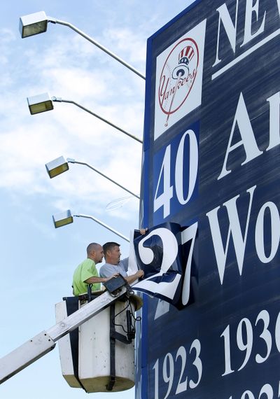 Chris Sessa, left, and Shawn Kunkle, employees of Signs USA Inc., in Tampa, Fla., change the numbers on the champ- ionship sign outside the New York Yankees’ minor league complex in Tampa.  (Associated Press / The Spokesman-Review)