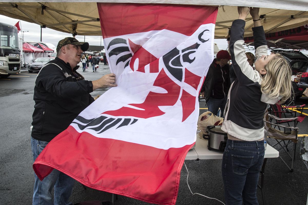 Matthew Pederson and Jennifer Druffell hang an EWU flag from a tent before the start of the Eastern Washington-Northern Iowa game, Sept. 17, 2016, in Cheney. (Dan Pelle / The Spokesman-Review)