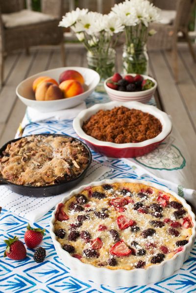 Take advantage of summer fruits at their peak with simple desserts such as this mixed berry clafoutis, front, peach, blueberry buckle with rum and pecans, center, or a ginger rhubarb crisp.