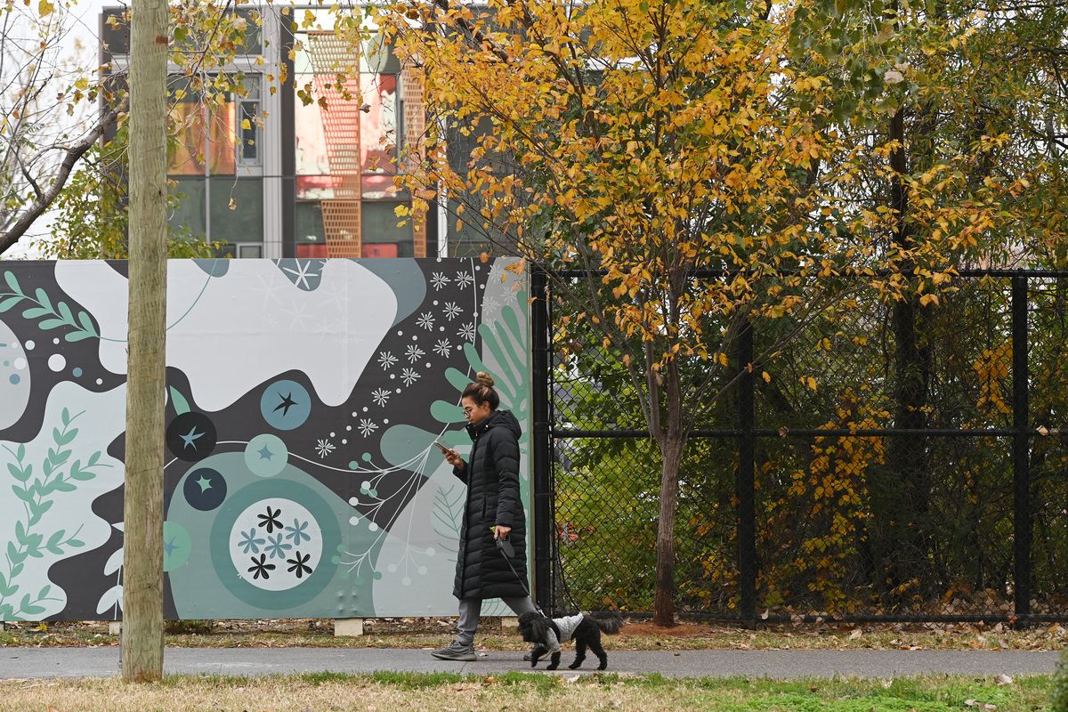 A pedestrian walks by a fence surrounding the site for the second phase of Amazon HQ2 in 2021. MUST CREDIT: Washington Post photo by Matt McClain.  (Matt McClain/The Washington Post)