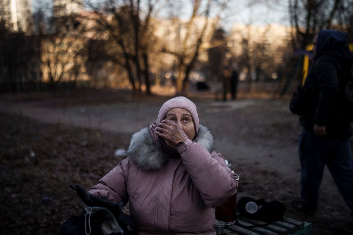 A woman reacts after being rescued by firefighters from her apartment in a burning building that was hit by artillery shells in Kyiv, Ukraine, Tuesday, March 15, 2022.  (Felipe Dana)