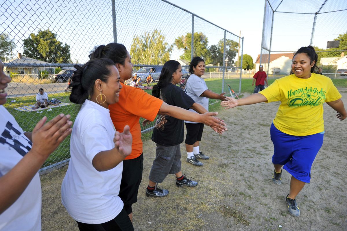 Jessica Betongtong, right, is greeted by teammates after she hit a home run during a Marshallese Community Softball League game on Friday at Rochester Heights Park. The Spokane Parks and Recreation Department is raising its fees for using sports fields next year, including the field where the Marshallese teams play, which do not receive regular maintenance like some city fields. (Dan Pelle)