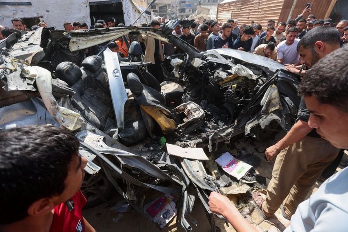 Palestinians inspect the site of an Israeli strike on a car in Khan Younis, on Sunday, in the southern Gaza Strip.  (Reuters )