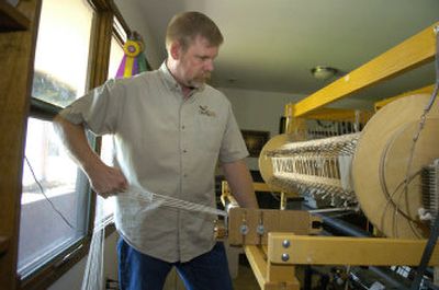 Michael Hickey winds the beam with alpaca fibers onto a loom in his shop, Quail Run Fiber Mill, in Airway Heights.
(Dan Pelle / The Spokesman-Review)