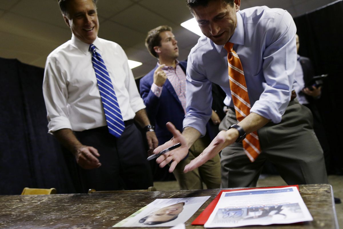 Republican vice presidential candidate Rep. Paul Ryan, R-Wis., right, jokes whether or not he should sign a photo of Republican presidential candidate and former Massachusetts Gov. Mitt Romney backstage at a campaign event at the Veterans Memorial Coliseum, Marion County Fairgrounds, in Marion, Ohio, Sunday, Oct. 28, 2012. (Charles Dharapak / Associated Press)