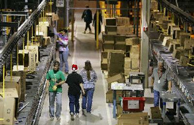 
An Amazon worker wearing a Santa hat walks past other workers Tuesday at the Amazon.com fulfillment center in Fernley, Nev. With the holidays just around the corner, many shoppers are relying on online sites like Amazon.com to complete their shopping. 
 (Associated Press / The Spokesman-Review)