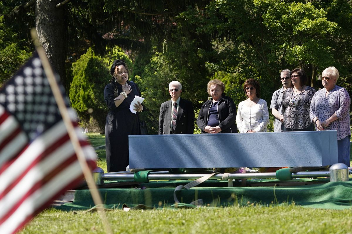 Edwina Frances Martin, Staten Island’s public administrator of estates, left, says a few words during a burial of four people at a cemetery in the Staten Island borough of New York, Thursday, June 17, 2021. The deceased died during the coronavirus pandemic and were being stored at a temporary morgue in Brooklyn. The facility is out of sight and mind for many for many as the city celebrates its pandemic progress but stands as a reminder of the loss, upheaval and wrenching choices the virus inflicted in one of its deadliest U.S. hotspots.  (Seth Wenig)