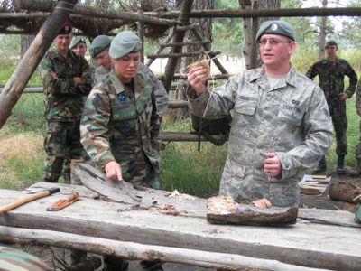 Airman 1st Class David Jones and Airman 1st Class Tiffany Zaloudek describe to the honorary commanders how to light a fire using a metal match and different kinds of kindling including straw and laundry lint.  (Lisa Leinberger / The Spokesman-Review)