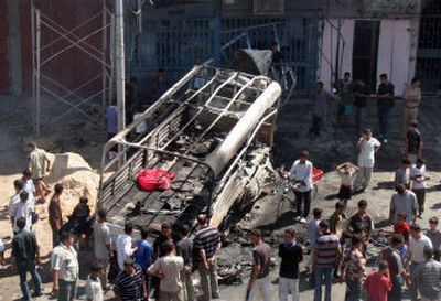 
Iraqis gather around a burned police truck at an explosion site in Baghdad's Dora neighborhood Thursday. Two suicide car bombers struck within a minute of each other in south Baghdad around noon Thursday, killing at least seven policemen. 
 (Associated Press / The Spokesman-Review)