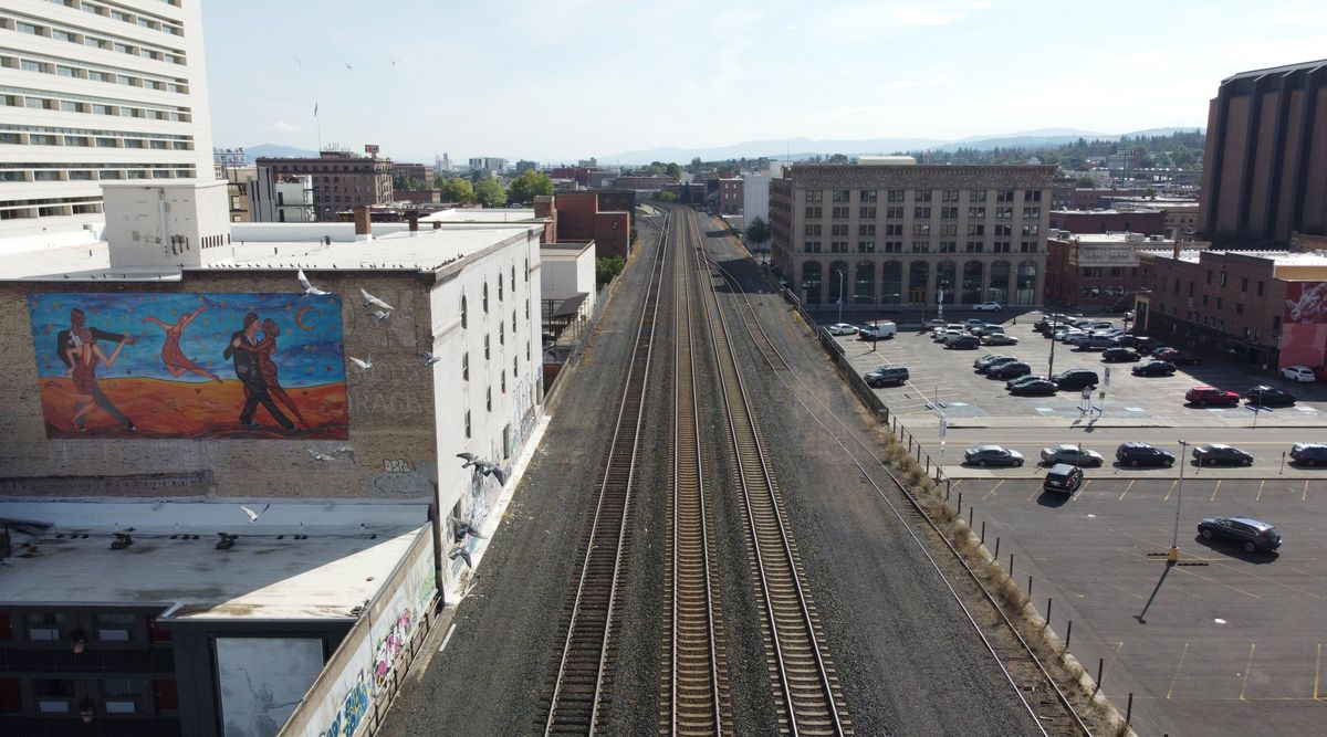 Present day: The main east-west rail tracks through Spokane ride on an elevated earthen viaduct through downtown. During the heyday of rail transportation, warehouses and commercial buildings that depended on regular train deliveries of retail goods surrounded the tracks. The Holley-Mason building is at upper right and the warehouse at center left was the 1900 Powell-Sanders grocery warehouse that was later expanded from three to five stories in 1915. Most of the surrounded warehouses have been torn down leaving ground level parking lots.  (Jesse Tinsley/THE SPOKESMAN-REVIEW)