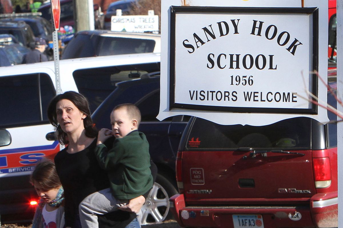 FILE — A parent walks away from the Sandy Hook Elementary School with her children following a shooting at the school in Newtown, Conn., Dec. 14, 2012. The families of nine victims of the Sandy Hook Elementary School shooting have agreed to a settlement of a lawsuit against the maker of the rifle used to kill 20 first graders and six educators in 2012, according to a court filing, Tuesday, Feb. 15, 2022. (Frank Becerra Jr.)