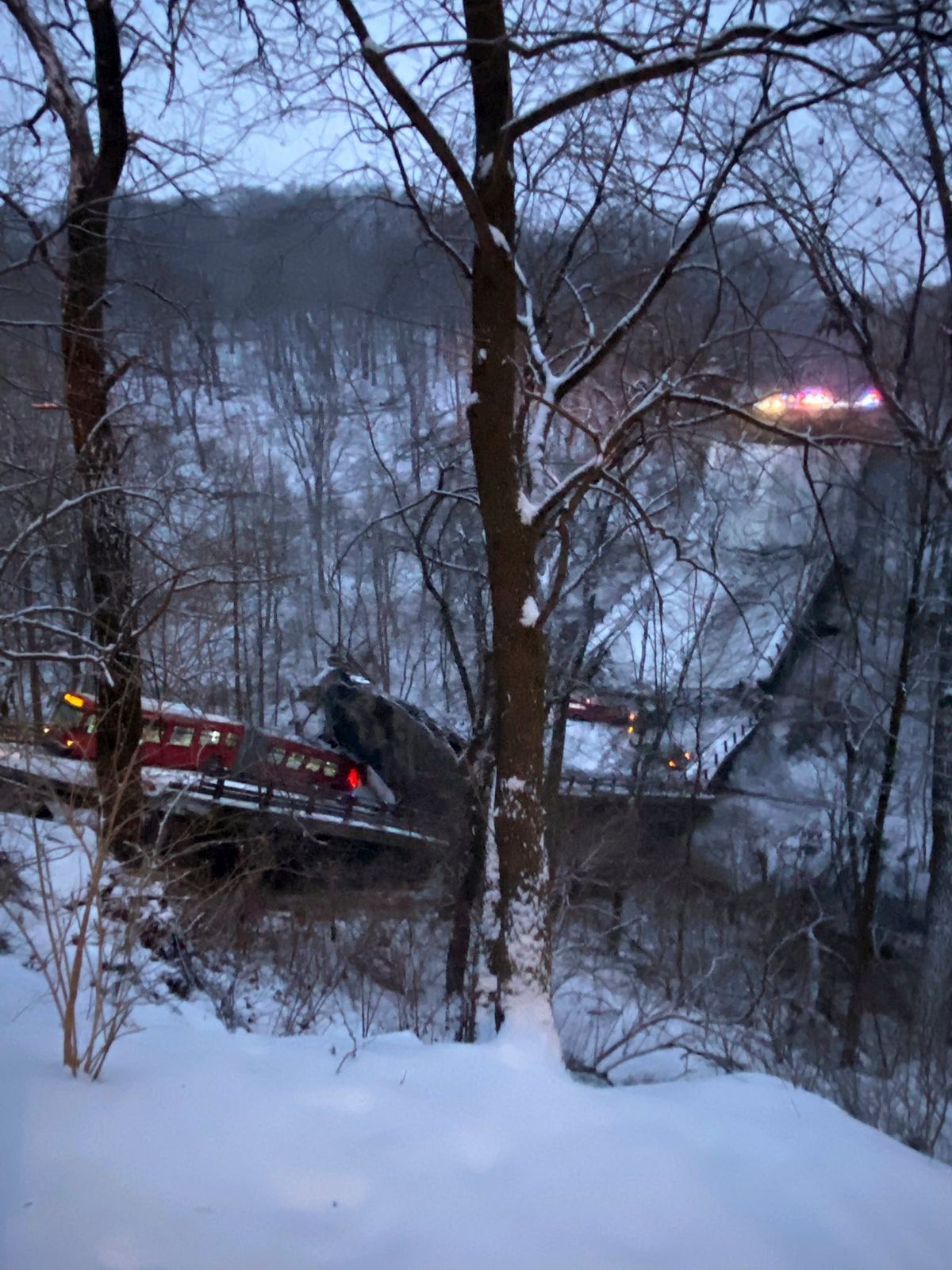 A commuter bus sits upright on a section of a collapsed bridge in Pittsburgh, on Friday, Jan. 28, 2022. Police reported the span, on Forbes Avenue over Fern Hollow Creek in Frick Park, came down around 6 a.m. There were no initial reports of injuries, Pittsburgh Public Safety said on Twitter.  (HONS)
