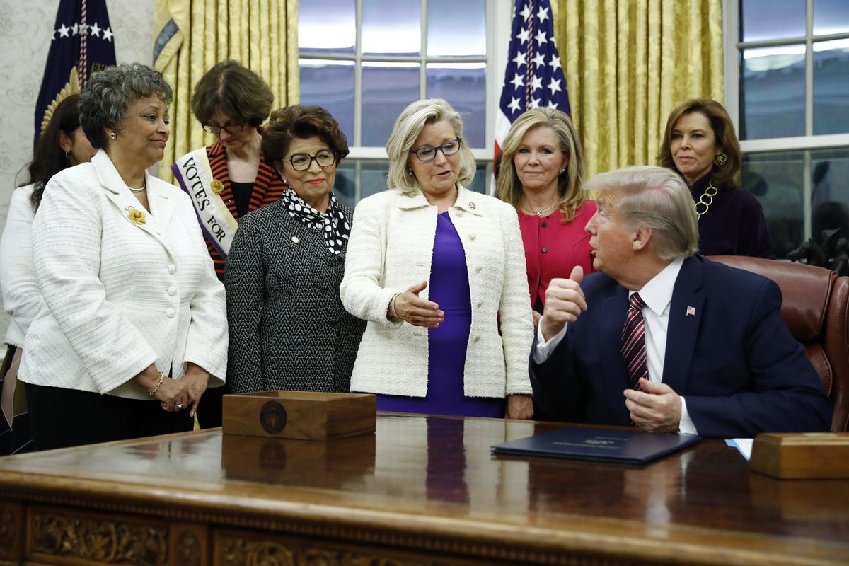 FILE - In this Nov. 25, 2019, file photo, Rep. Liz Cheney, R-Wyo., center, speaks with President Donald Trump during a bill signing ceremony for the Women