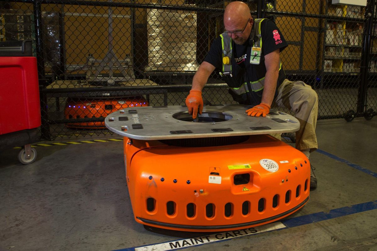Barry Tormoehlen, a maintenance technician at Amazon’s fulfillment center in DuPont, Washington, vacuums the inside of a KIVA, one of the company’s robots that are used to move items around the center, Monday, July 3, 2017. (Tribune News Service)