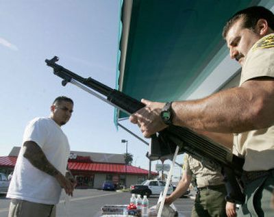 
Larry Espinosa turns in a rifle to Los Angeles County sheriff's deputy David Motts during a Gifts For Guns program in Compton, Calif., Saturday. 
 (Associated Press / The Spokesman-Review)