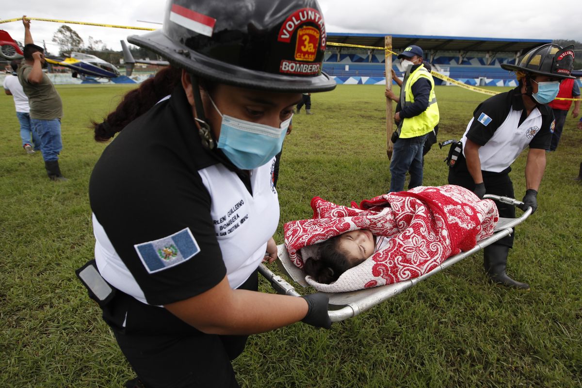 A girl rescued from the zone where residents are believed buried by a massive, rain-fueled landslide, is carried on a stretcher to a waiting ambulance during a search and rescue operation, in San Cristobal Verapaz, Saturday, Nov. 7, 2020, in the aftermath of Tropical Storm Eta.  (Moises Castillo)