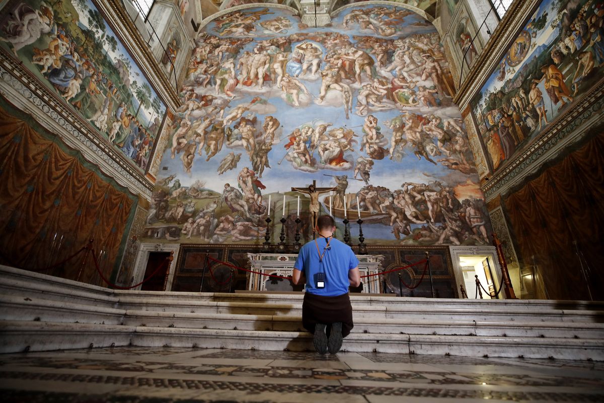 A visitor kneels in front of the Last Judgement fresco by the Italian Renaissance painter Michelangelo inside the Sistine Chapel of the Vatican Museums on the occasion of the museum