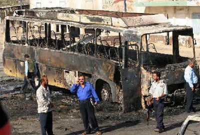 
Iraqi police officers secure the area around a passenger bus destroyed by two massive car bombs that exploded  at the Nahda station in central Baghdad.
 (Associated Press / The Spokesman-Review)