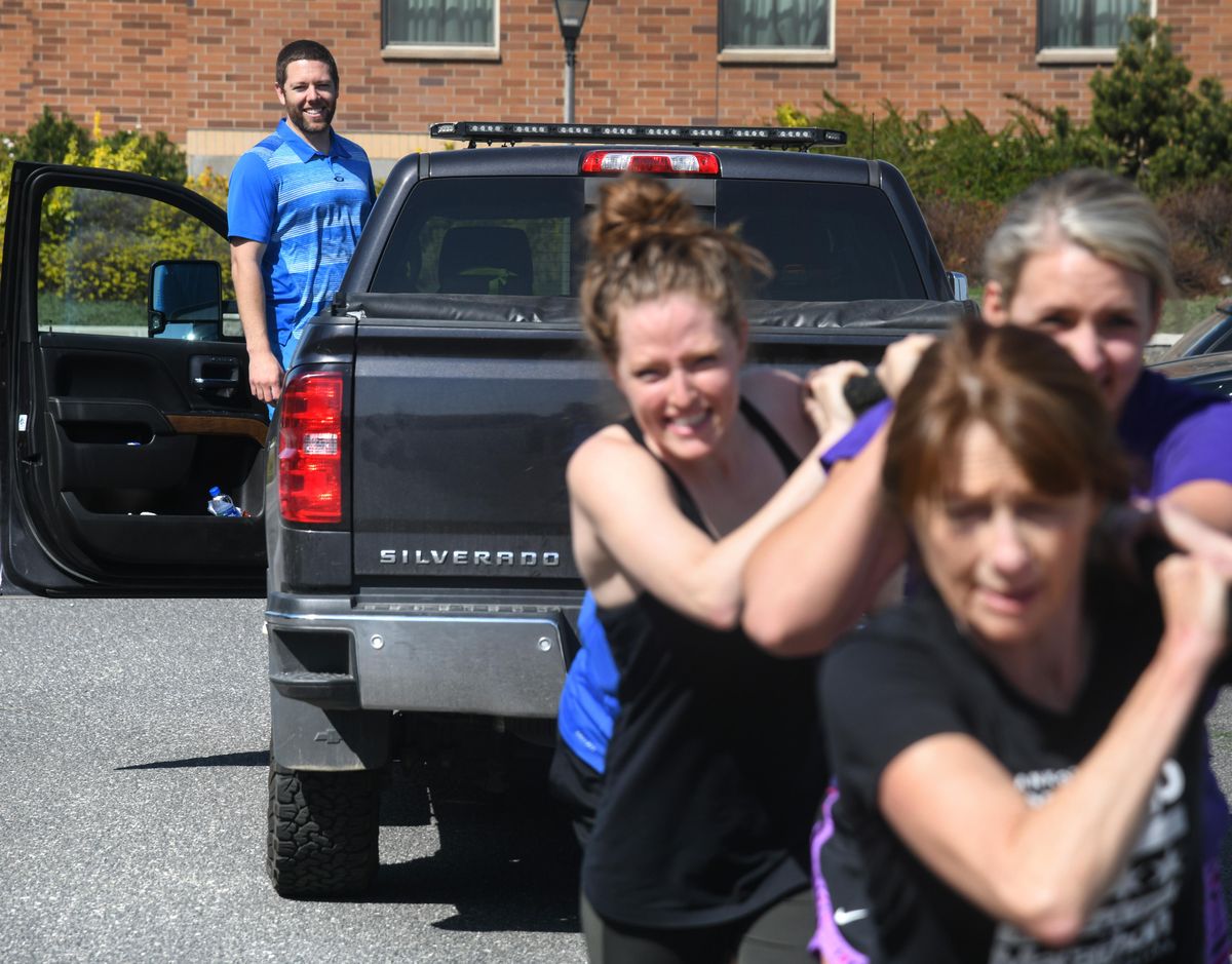 Ryan Hite, a physical therapist at U-District Physical Therapy, also operates  the business  Negative Split, which organizes road races. Here he oversees a class as it pulls his pickup truck with a rope during a training session. (Dan Pelle / The Spokesman-Review)
