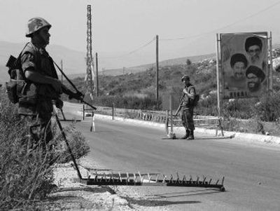 
Lebanese soldiers man a checkpoint next to a placard showing Hezbollah leader Sheik Hassan Nasrallah, bottom, on the border road with Israel going to Markaba, south Lebanon, on Saturday. 
 (Associated Press / The Spokesman-Review)
