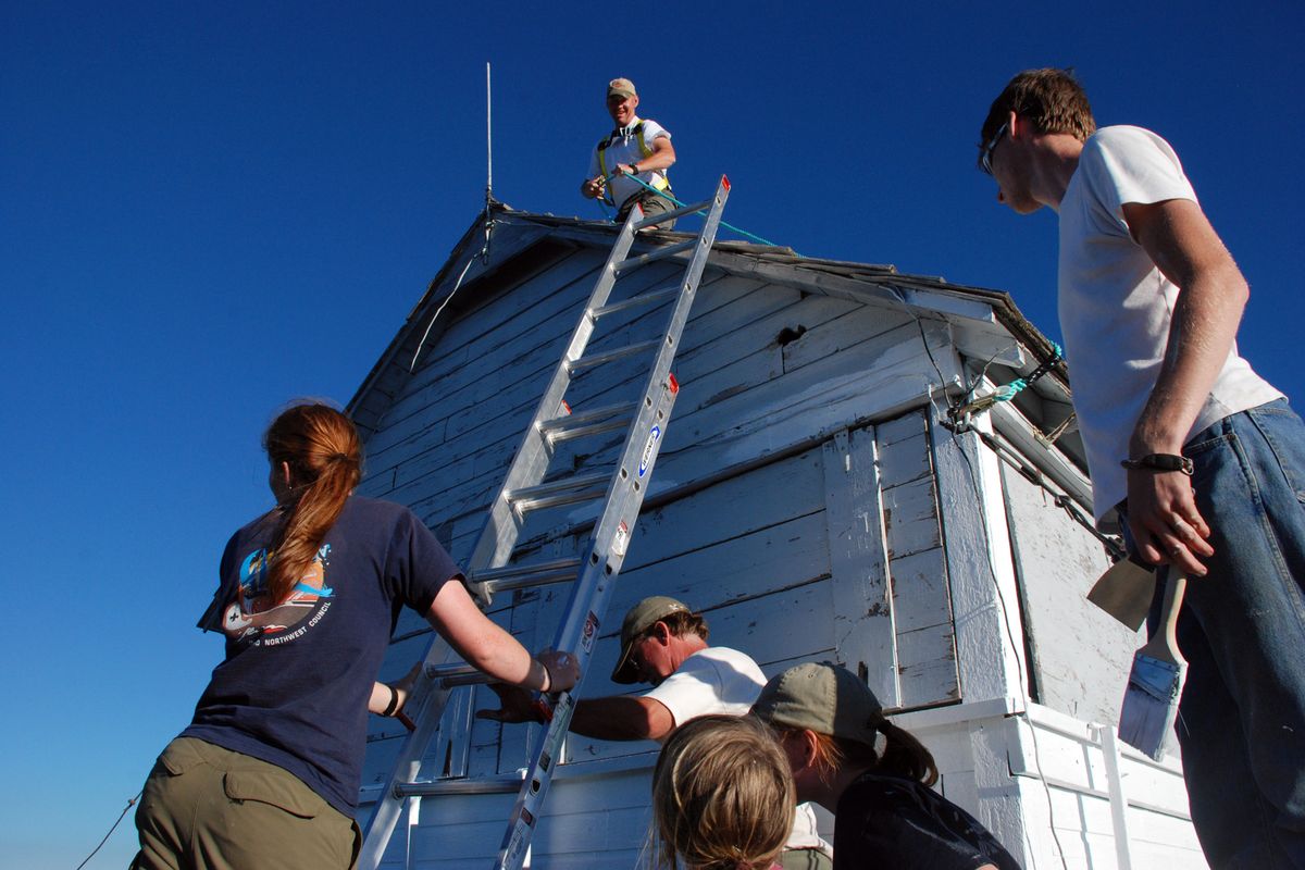 Tim Grubham of St. Maries, Idaho, fixes the stove pipe while his family and other volunteers stick to the ground as they paint and restore Mallard Peak lookout. (Rich Landers / The Spokesman-Review)