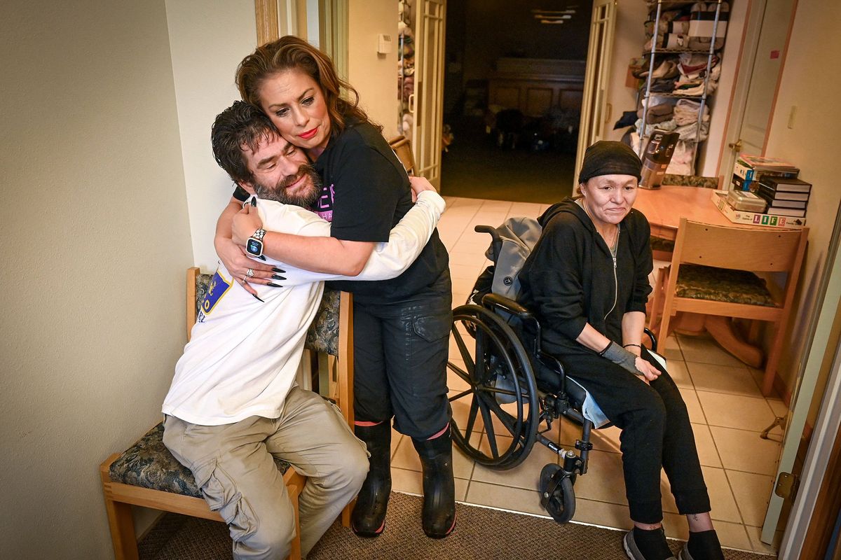 Julia Garcia, of Jewels Helping Hands, dishes out hugs to Jason Foster, left, and Barbara Bishop, both guests at the New Apostolic Church warming center on Monday in Spokane. Garcia says she likes to refer to the guests as family.  (DAN PELLE/THE SPOKESMAN-REVIEW)