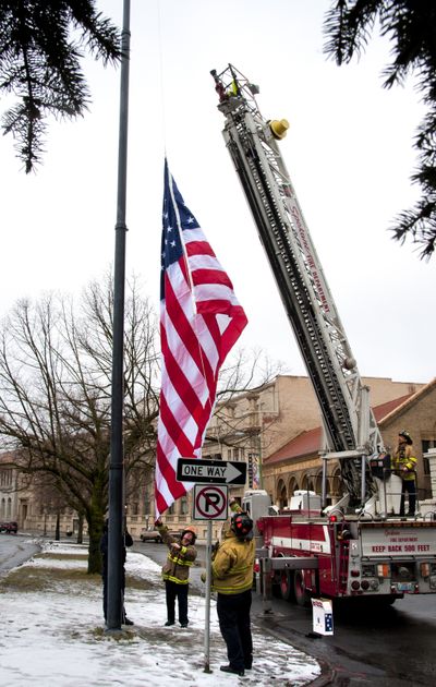 Raising the colors: It took Spokane Fire Department’s tallest ladder truck to fix a flagpole outside the Spokane Club and replace a weathered rope and flag. The 105-foot pole had been flagless for about two weeks, the club’s lead building engineer, Pat Savage, said. A previous attempt to reach the flag failed when fire crews realized an 85-foot ladder truck from Station 2 wouldn’t do the job. Though the city of Spokane owns the property, the club shines a spotlight on the flag every night. Firefighter Randy Marler, left, and Lieutenant D.J. Hill, center, raise the American flag Wednesday morning. (Dan Pelle)