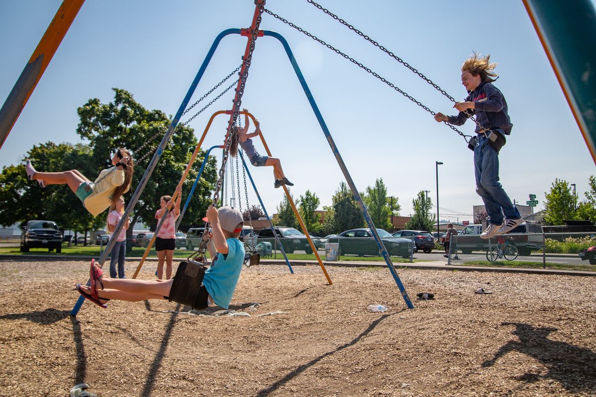 Children enjoy a swing set at Harmon Park on Aug. 4, 2019, during the final day of the Hillyard Festival. The family-friendly fun included a car show, vendors, nondenominational worship, booths and games.  (Libby Kamrowski)