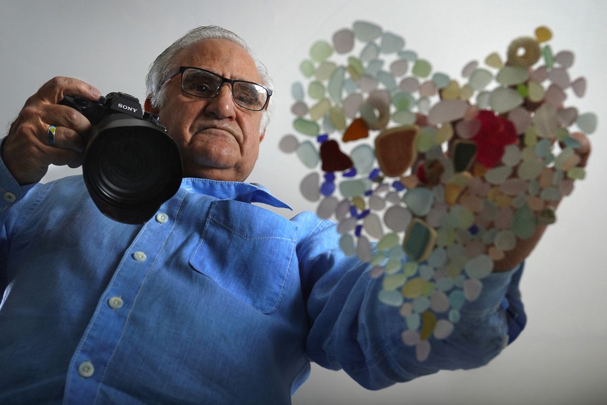 Donald Verger arranges sea glass in the shape of a heart Thursday in Falmouth, Maine. After photographing his art, Verger donates photos and cards as a way of giving back during the pandemic.  (Robert F. Bukaty)