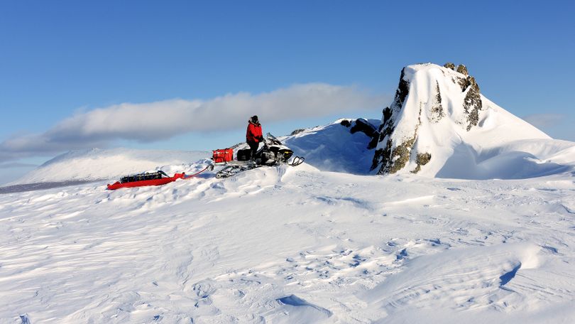 Josh Rindal of Spokane comes by a unique rock uplift on the Iditarod Trail with Little McKinley in the background. Rindal and Bob Jones of Kettle Falls were snowmobiling 1,400-miles along the route of Alaska's famous Iditarod Sled Dog Race in March 2014. (Robert Jones)