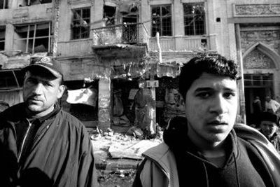 
Iraqis stand in front of a building and a mosque damaged in a blast in Baghdad, Iraq,  on Thursday. A parked car bomb that targeted a police patrol killed two officers and two civilians. 
 (Associated Press / The Spokesman-Review)