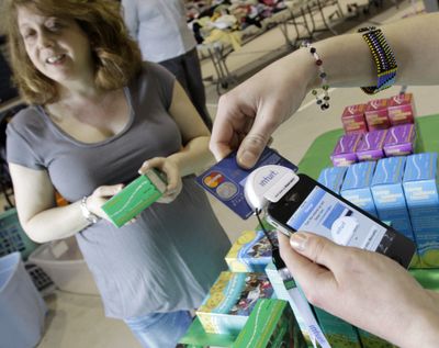 Alison Borodkin, of Solon, Ohio, waits for Girl Scout Caroline Moore to run her credit card for the purchase of some Girl Scout cookies on Monday. Girl Scout troops in Ohio are using GoPayment to accept credit card payments. (Associated Press)