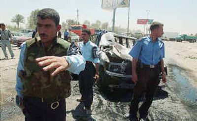 
Iraqi policemen secure the site of a car-bomb attack in which 12 people were killed, among them four Iraqi policemen, on Sunday in Baghdad. 
 (Getty Images / The Spokesman-Review)