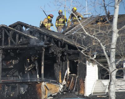 Firefighters look for hot spots Wednesday in the attic of a building at an apartment complex at Broadway Avenue and Vercler Road in Spokane Valley. Everyone in the 12-unit building was evacuated and one man went to the hospital with minor burns. (Jesse Tinsley)