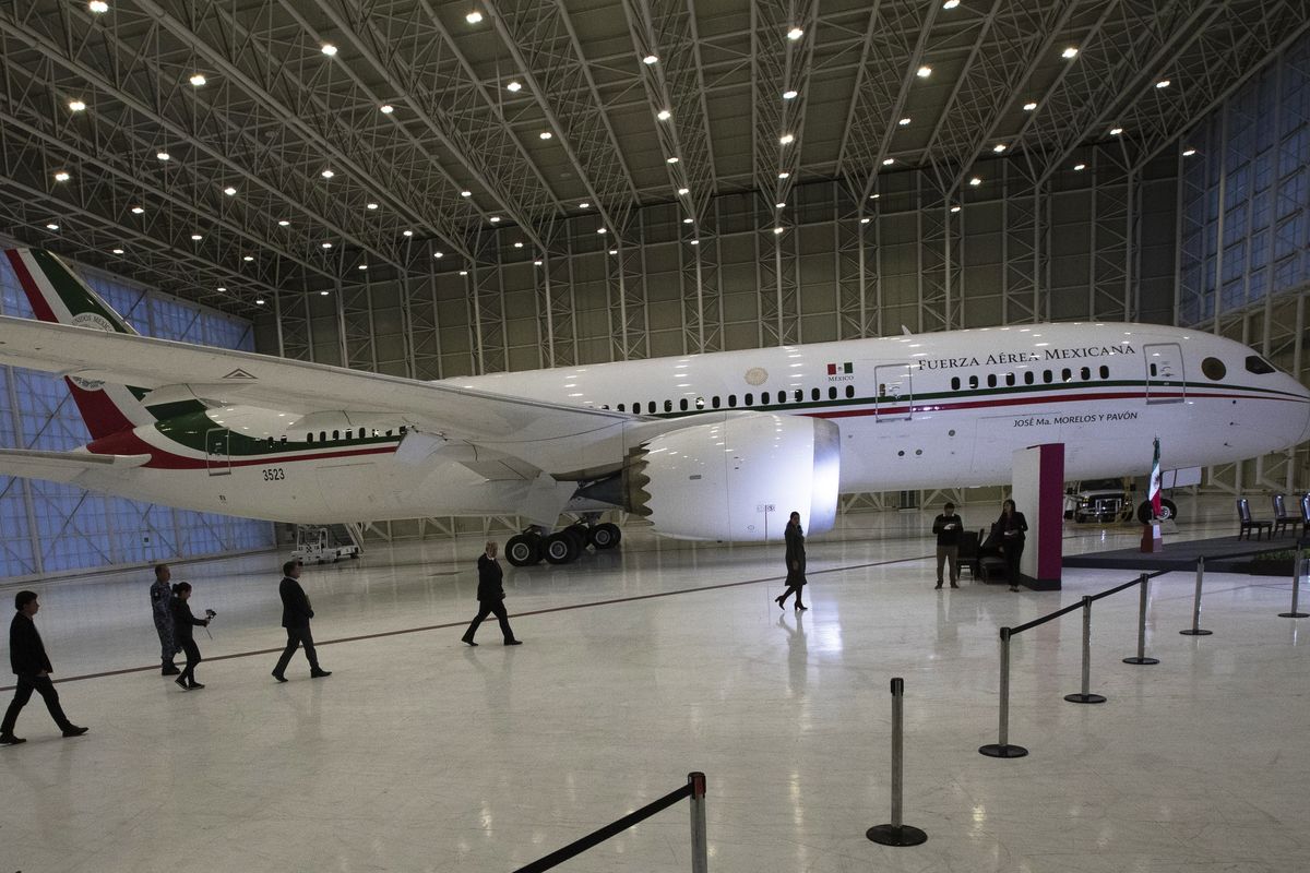 FILE - In this July 27, 2020 file photo, Mexican President Andres Manuel Lopez Obrador, center left, waves to the press as he arrives to give his daily, morning press conference in front of the former presidential plane at Benito Juarez International Airport in Mexico City. López Obrador’s quixotic bid to sell off the presidential jet has now stretched into its third year in 2021, with no sign of a buyer in sight.  (Marco Ugarte)