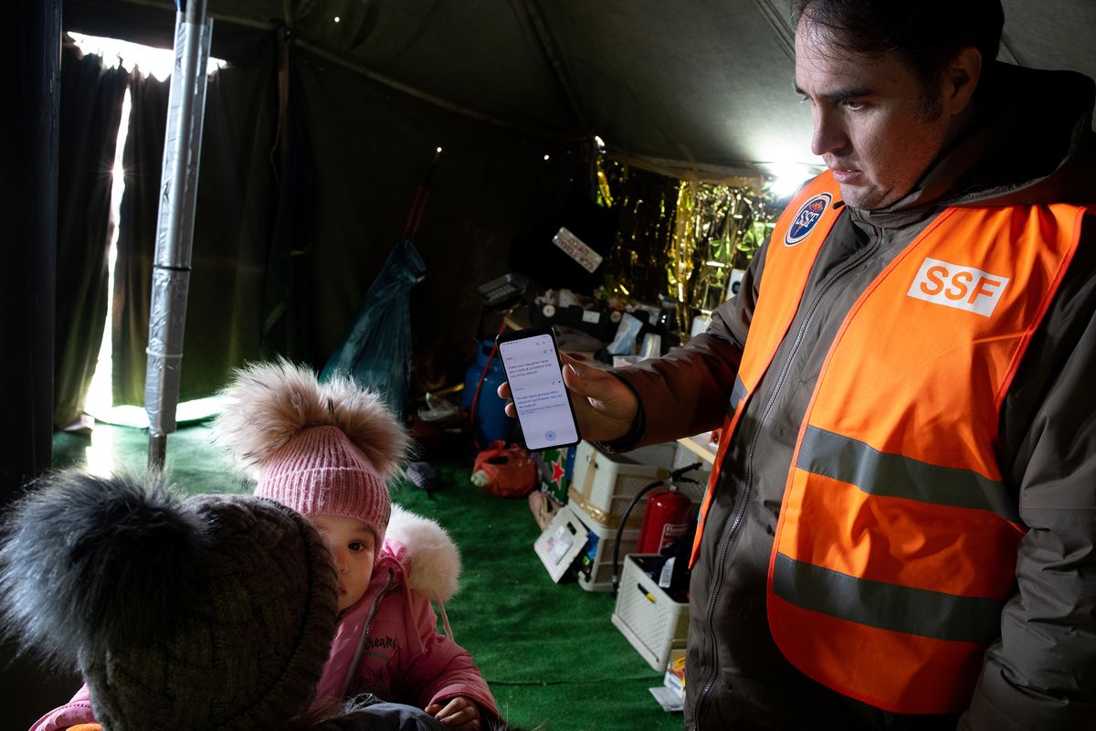 Kyle Varner uses a translation application to diagnosis a 1.5-year-old’s ailment. The little girl, who had spent three days fleeing the war in Ukraine, had an ear infection.  (Eli Francovich/The Spokesman-Review)