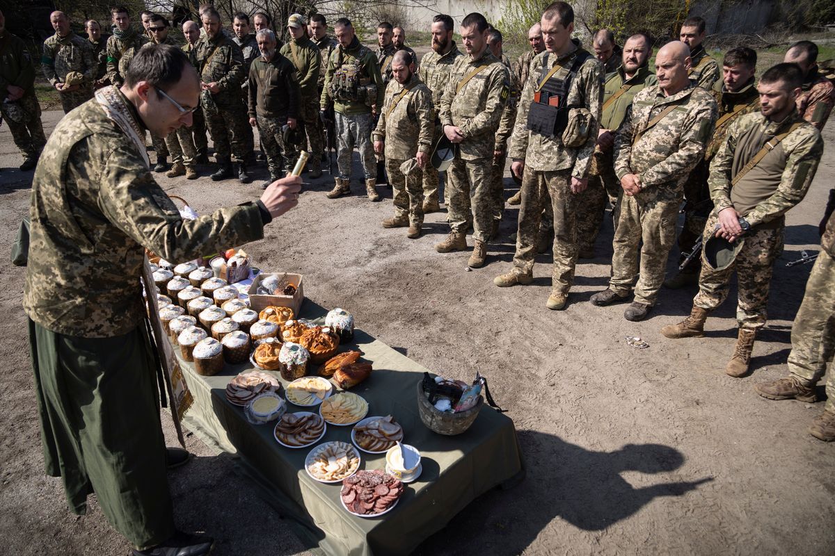 A military Orthodox priest blesses traditional food during the Easter celebration at the frontline position of 128 brigade of Ukrainian army near Zaporizhzhia, Ukraine, Sunday, April 24, 2022.  (Andriy Dubchak)