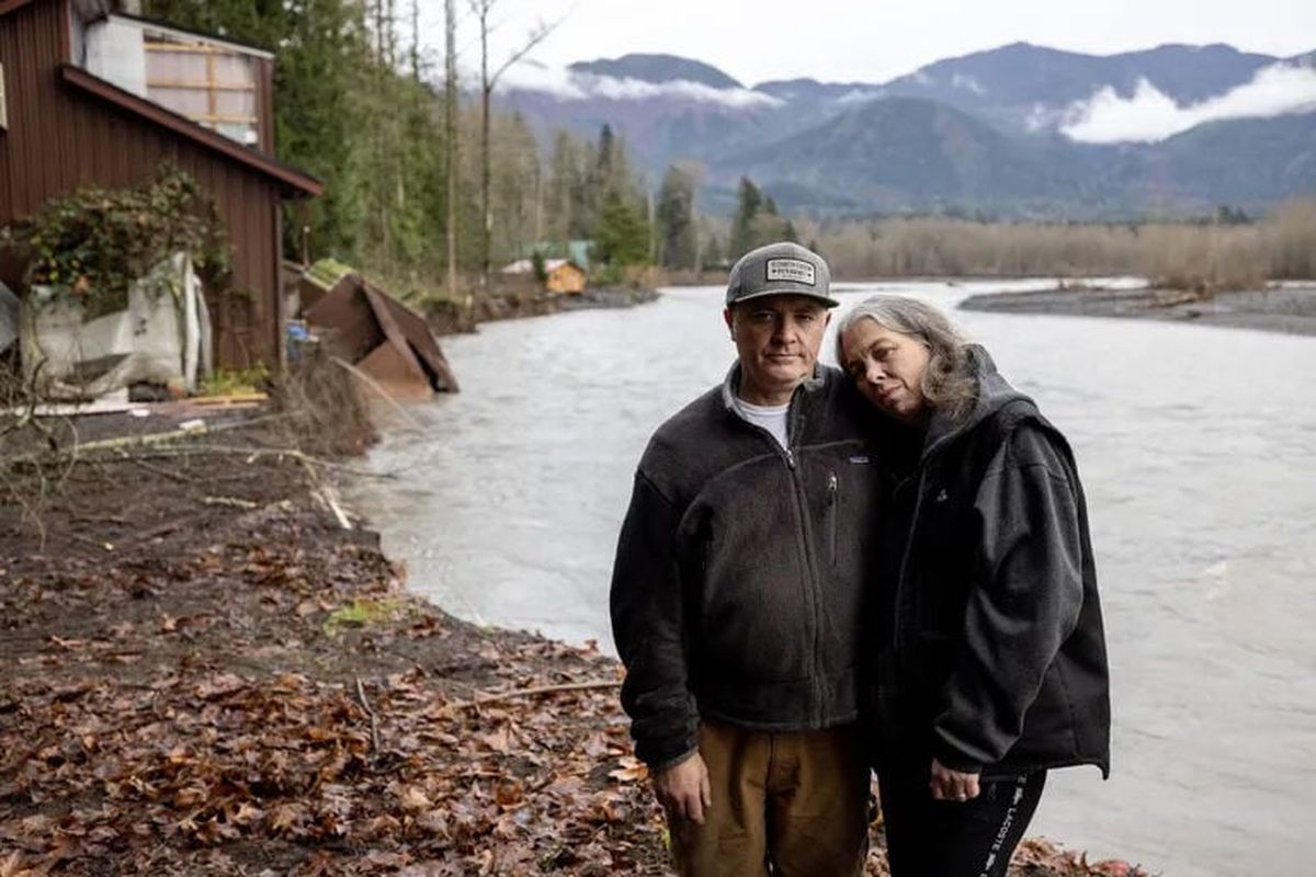 Mike Khazak and his partner Sarah Hansen pose for a photo Sunday near where their house stood in Deming, Whatcom County. The Nooksack River eroded the land and took their house with it Thursday morning, leaving behind only a garage. (Nick Wager/Seattle Times)