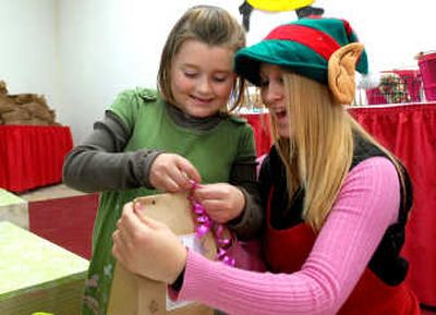 
Volunteer Sarah Clifton helps Jennifer Rossey, 7, wrap gifts for her family at the Santa Express store Friday. The store lets children ages 4 to 12 shop for inexpensive gifts for friends and family and wrap them with the help of a volunteer. Prices range from 50 cents to $7.50. 
 (Jesse Tinsley / The Spokesman-Review)