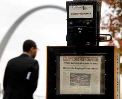 A man walks past a St. Louis Post-Dispatch newspaper box with s the Gateway Arch in the background in St. Louis in November 2009.  (Associated Press)