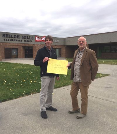 From left, Randy Ahmann and Tom Moore display a thank-you card made for them by Shiloh Elementary schoolchildren outside the school after a delivery. (Courtesy of Tom Moore)