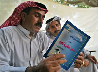 
Iraqis read a draft of the country's constitution in Baghdad on Wednesday. Iraq's National Assembly voted  to reverse last-minute changes it had made to rules for next week's referendum on a new constitution.  
 (Associated Press / The Spokesman-Review)