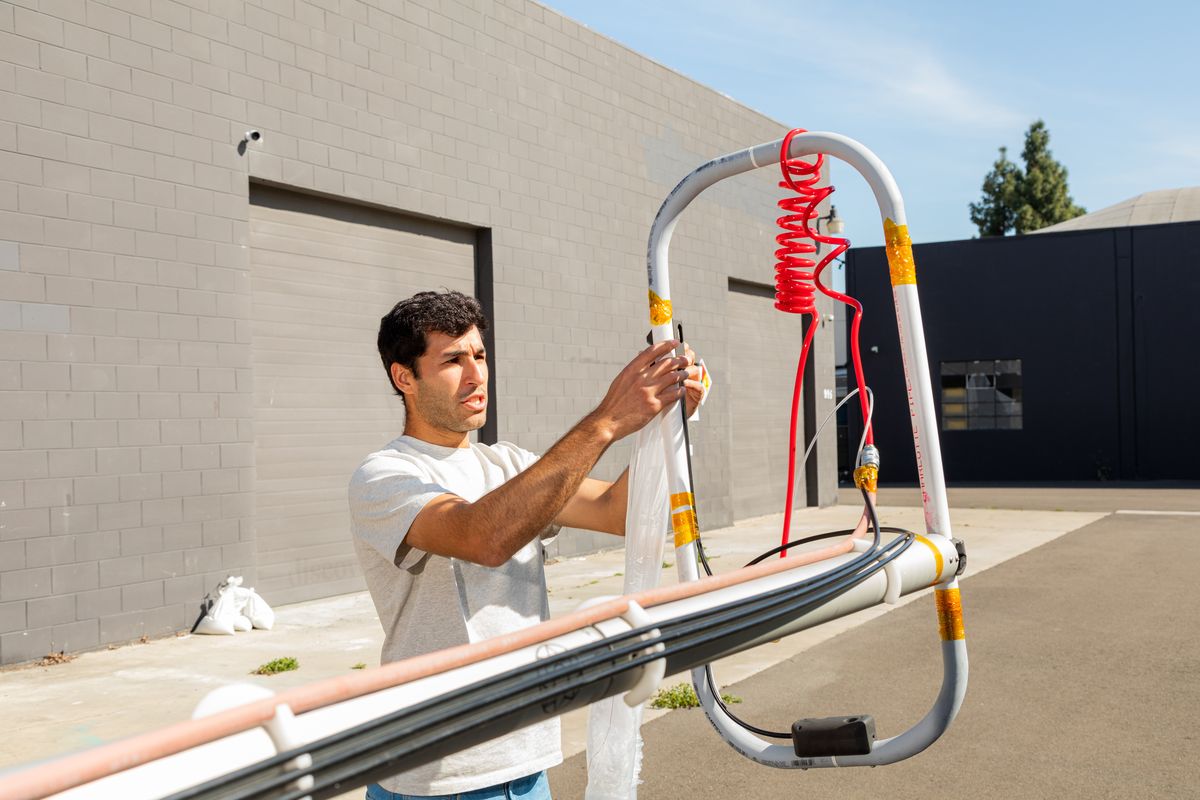 Jehan Godrej, WindBorne launch operations coordinator, attaches a weather balloon to a mechanism that will fill it with helium and send it skyward on April 29 at Windborne headquarters in Palo Alto, Calif. (JASON HENRY/New York Times)