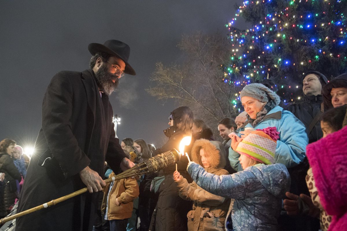 Rabbi Yisroel Hahn lights the candles of people who came to watch the lighting of the Hanukkah menorah in Riverfront Park. (Jesse Tinsley / The Spokesman-Review)