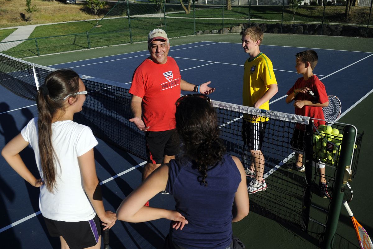 Frank Cruz-Aedo, the passionate president of the Liberty Lake Community Tennis Association, explains how tennis is scored to a group of beginner tennis players during open tennis night at Rocky Hill Park on Aug. 1. (J. Bart Rayniak)