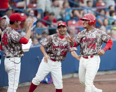 Spokane Indians's Marcus Greene, right, is congratulated by teammates Luis Pollorena, center, and pitching coach Jose Jaimes after scoring a run. (Tyler Tjomsland)