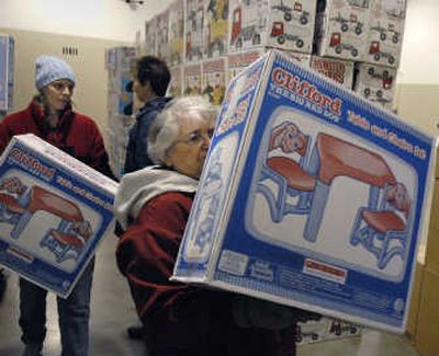 
Bonnie Atkinson, left, and Maxine Adamson stack boxes of Clifford The Big Red Dog Table and Chair sets at the Christmas Bureau located at the Spokane County Fair and Expo Center on Wednesday. 
 (Dan Pelle / The Spokesman-Review)