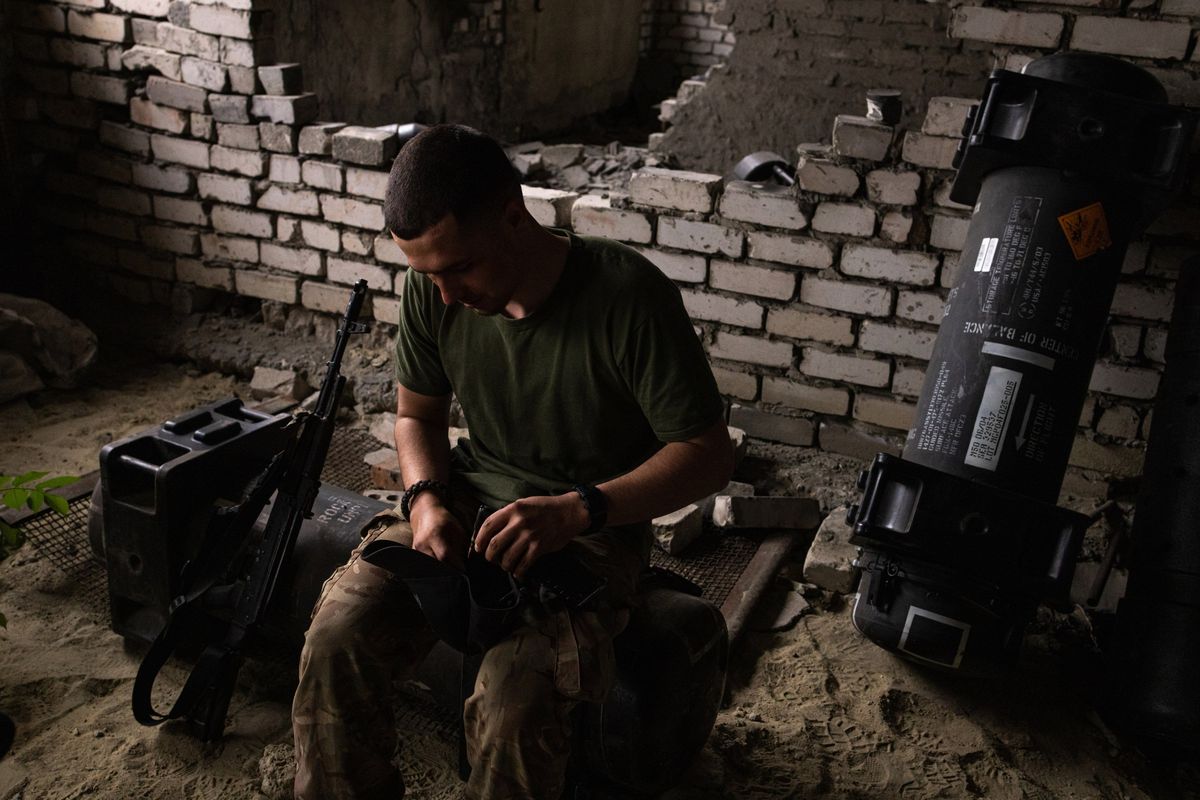 A Ukrainian soldier, who identified himself by his call sign, Stus, sits on an empty Javelin missile container near the front lines on July 21. Ukrainian soldiers are using the empty containers for several purposes, including sleeping.    (Serhiy Morgunov/For The Washington Post)