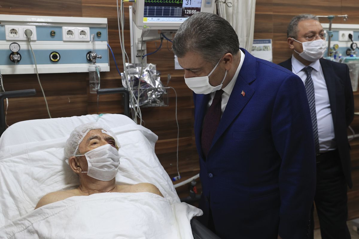 Turkey’s Health Minister Fahrettin Koca speaks with Ahmet Citim, rescued from the debris of his collapsed house in Izmir, Turkey, on Sunday.  (POOL)